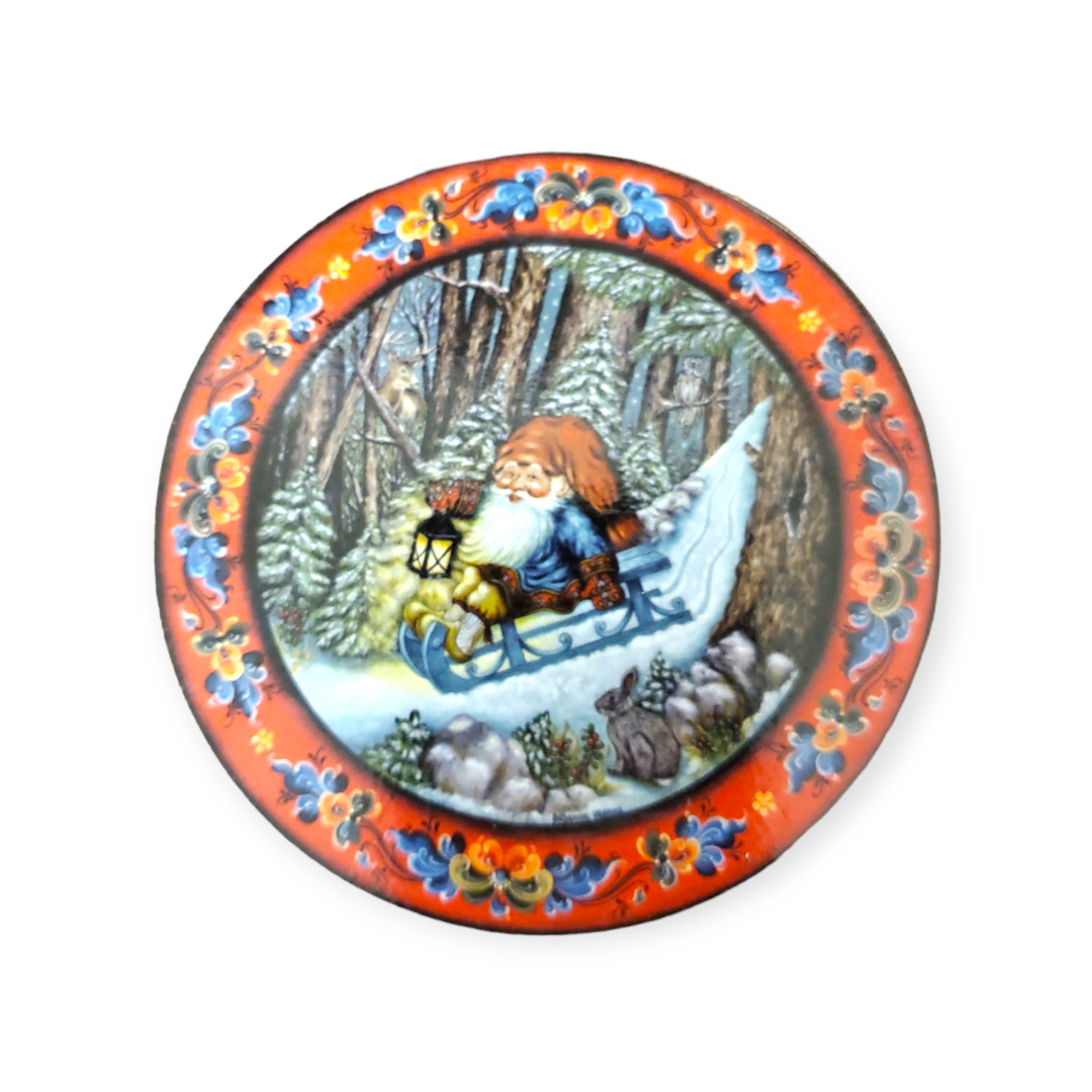 Decorative coaster set featuring a wintry scene with a Tomte on a sled, carrying a lantern through snowy trees, accompanied by a rabbit and the Christmas Goat, all encompassed by a colorful floral border that exudes Julestemning.