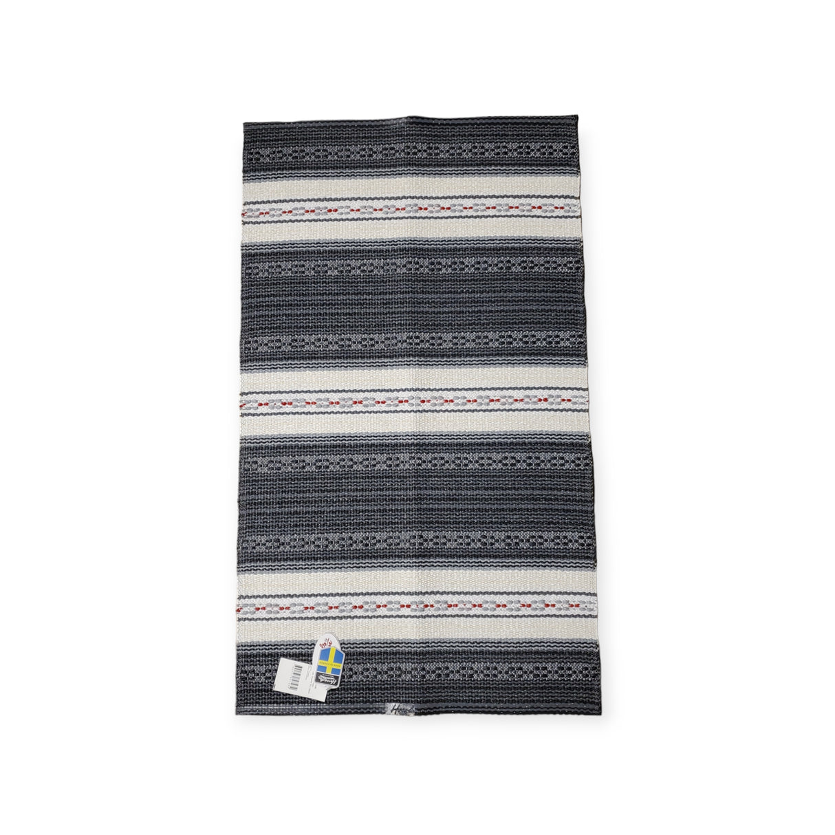 The Astor Graphite rug is a robust Swedish vinyl piece featuring a tag with the Swedish flag. Its non-skid fabric displays stylish horizontal stripes in black, white, and red for added safety.
