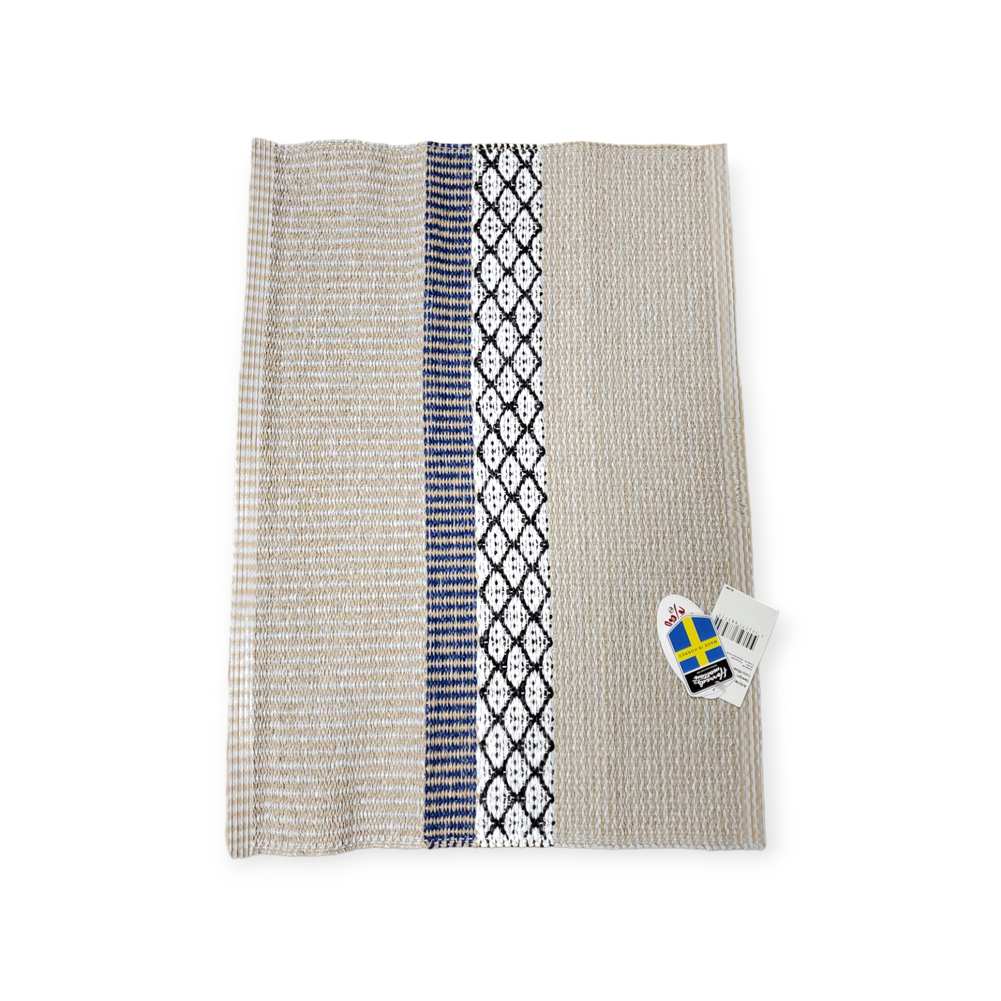 The Rug: Savanne Blue Vinyl is a woven textile showcasing beige, blue, and black patterns. It comes with a Swedish flag sticker and barcode label, evoking the timeless appeal of a classic Horredsmattan Swedish vinyl rug while providing a maintenance-free solution for modern homes.