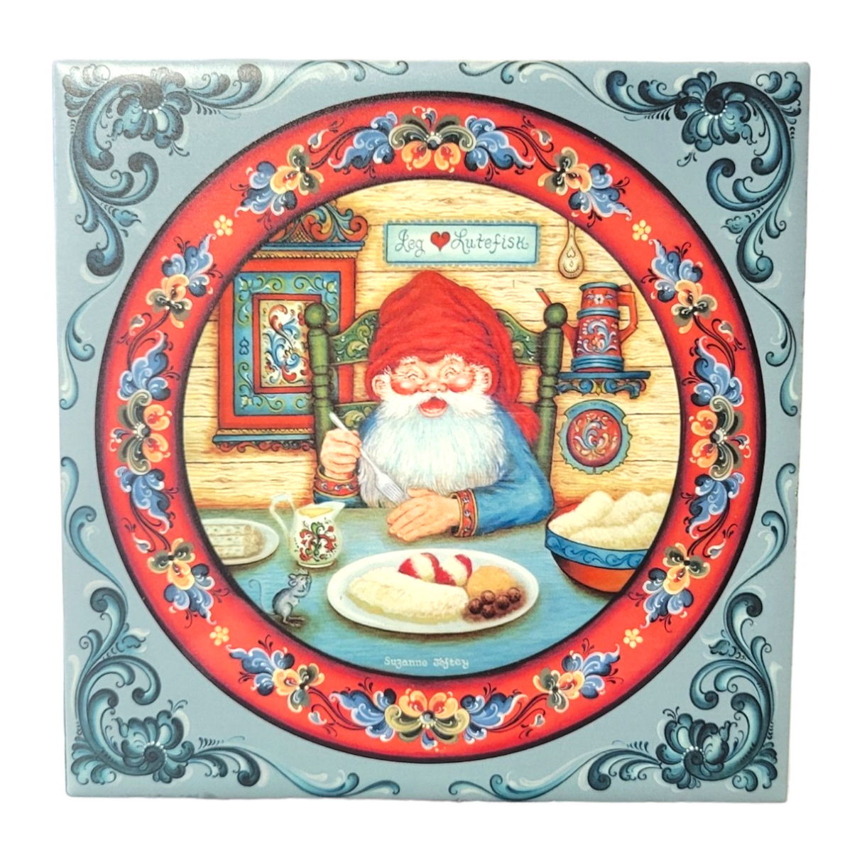 The Tile: Santa Eats Lutefisk 6" Tile with Norwegian Rosemaling features a festive illustration of Santa Claus savoring lutefisk, surrounded by ornate borders in the traditional Norwegian Rosemaling style and a sign saying God Julefest, embodying the spirit of a Scandinavian Christmas.