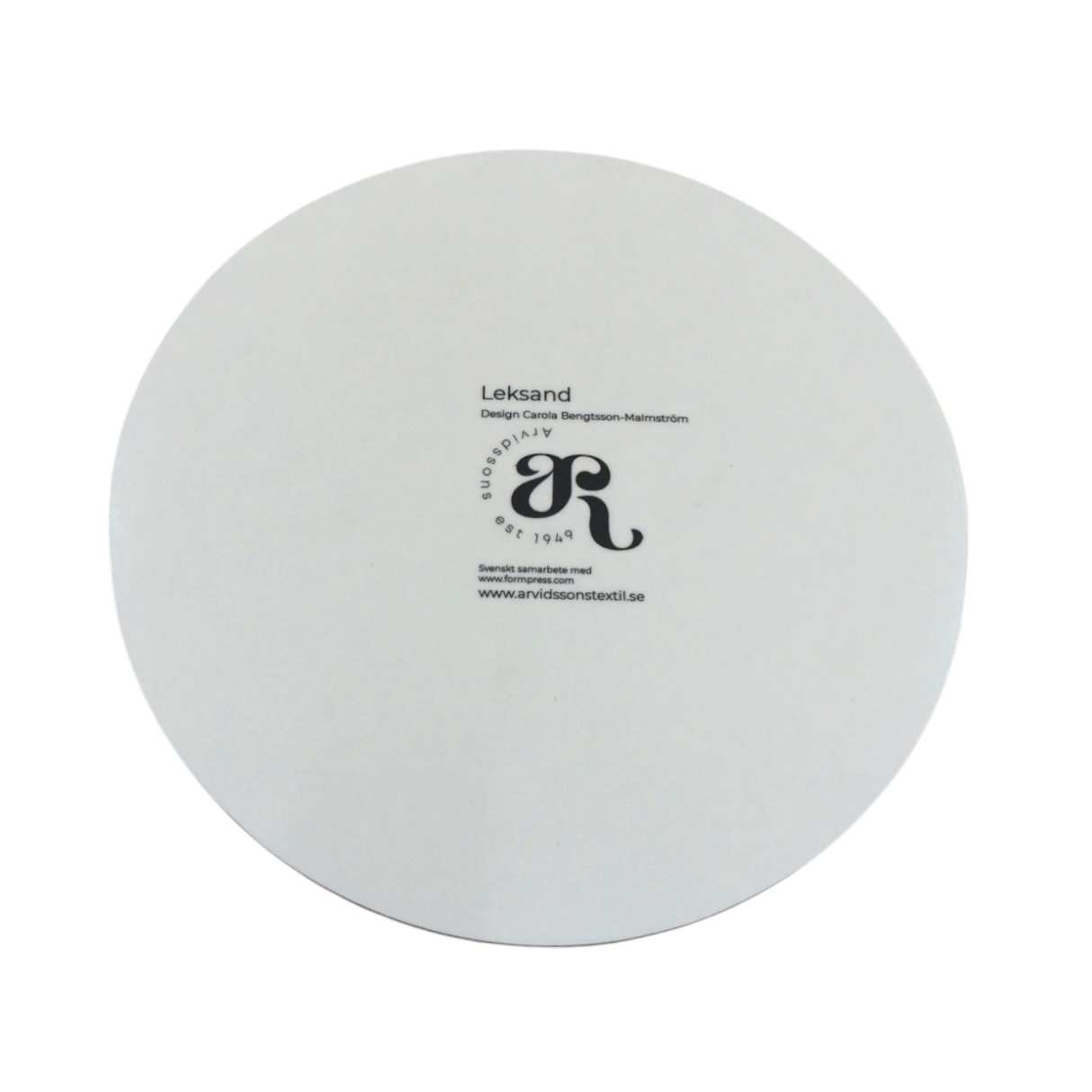 White circular plate featuring the Leksand Cream Circular Trivet design by Carine Bengtsson for Arvidssons Textil, inspired by Dala horses, with Leksand, a logo, and a web address.