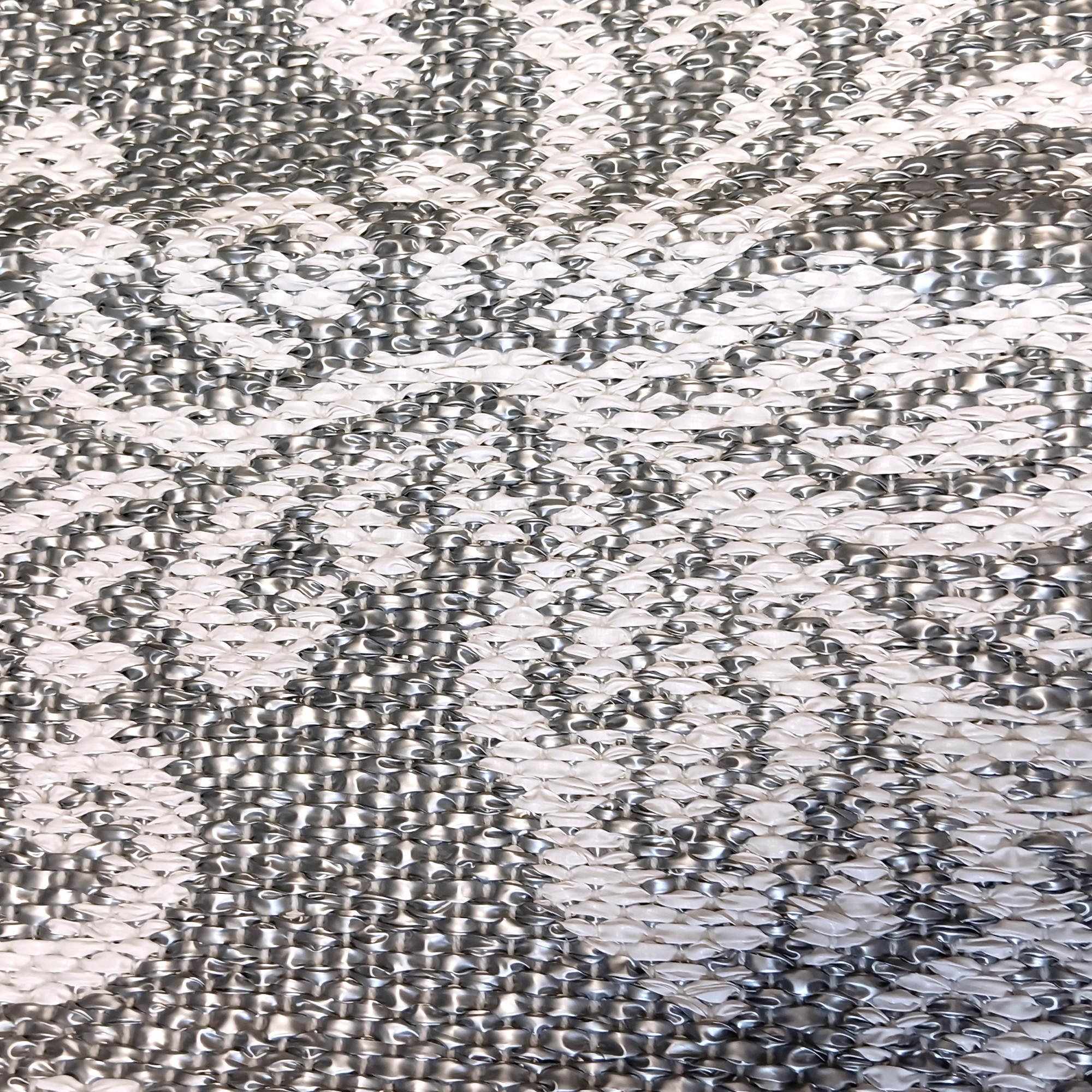 Close-up of the Swedish Dala Horse Rug with Kurbits in Silver & White, showing a textured surface with shiny and matte raised areas that create an abstract design inspired by traditional Swedish rug motifs.