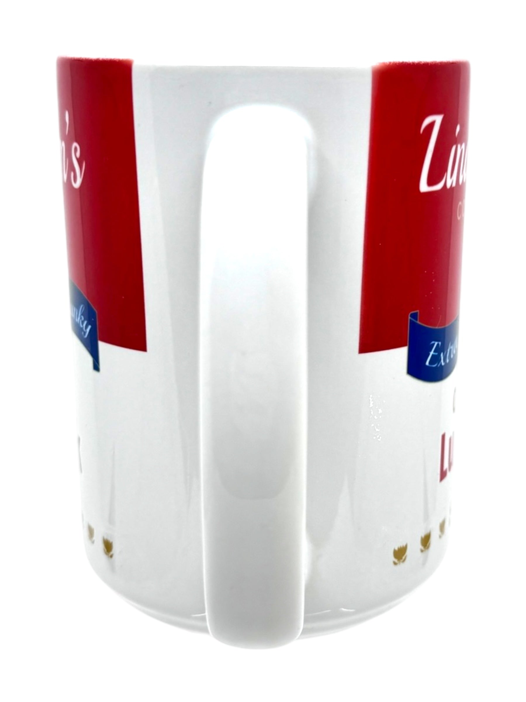 The Coffee Mug: Lindstrom's Cream of Lutefisk Soup (11oz) is shown white with its handle forward, partially obscuring red and blue text and graphics on the mug’s surface.