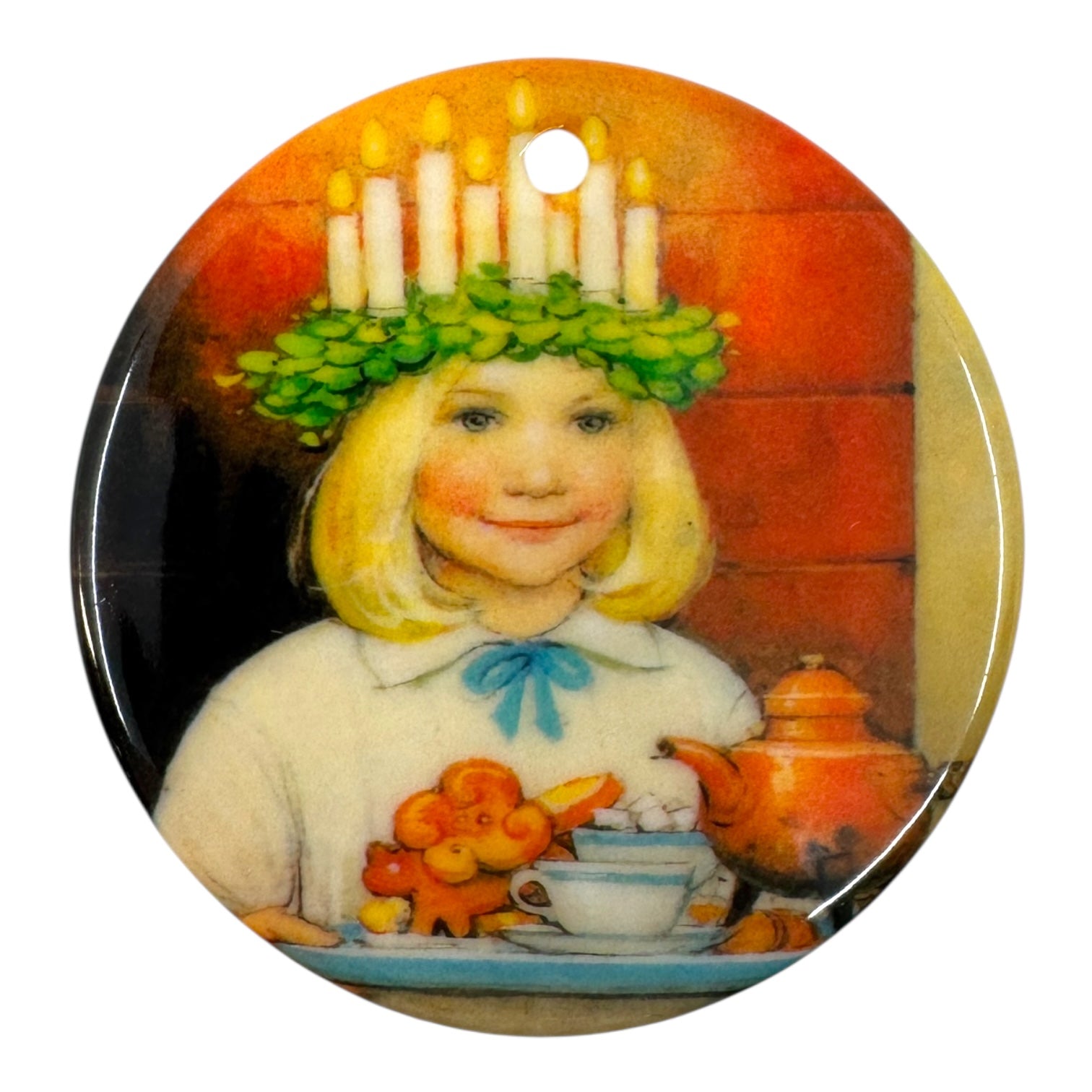 A blonde girl with a candle crown carries a tray of teapot, cup, and cinnamon buns in this 3 St Lucia Porcelain Ornament—a charming handcrafted keepsake for your holiday décor.
