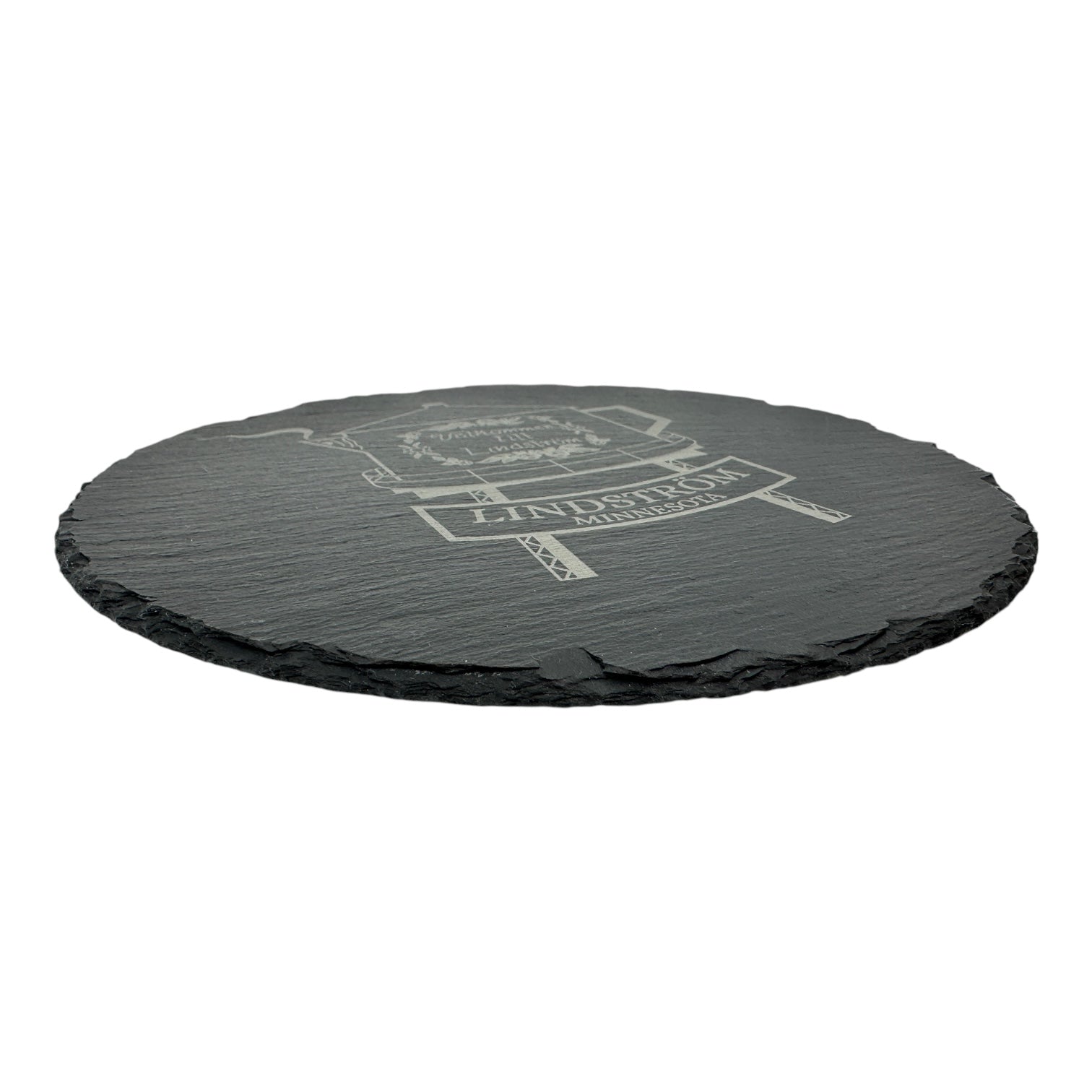A round, black 9.75 slate trivet engraved with the Lindstrom Coffee Pot Water Tower—a famous Minnesota landmark—shown against a white background.