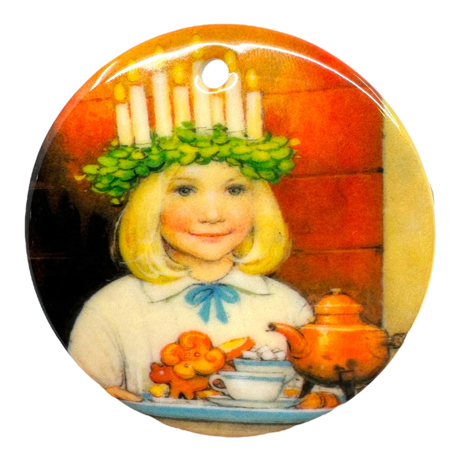 A girl with a candle crown and green wreath carries a tray of teapot, cups, and cinnamon buns, smiling warmly—a delightful 3 porcelain ornament: Ornament: St Lucia with Cinnamon Buns, perfect for festive décor.