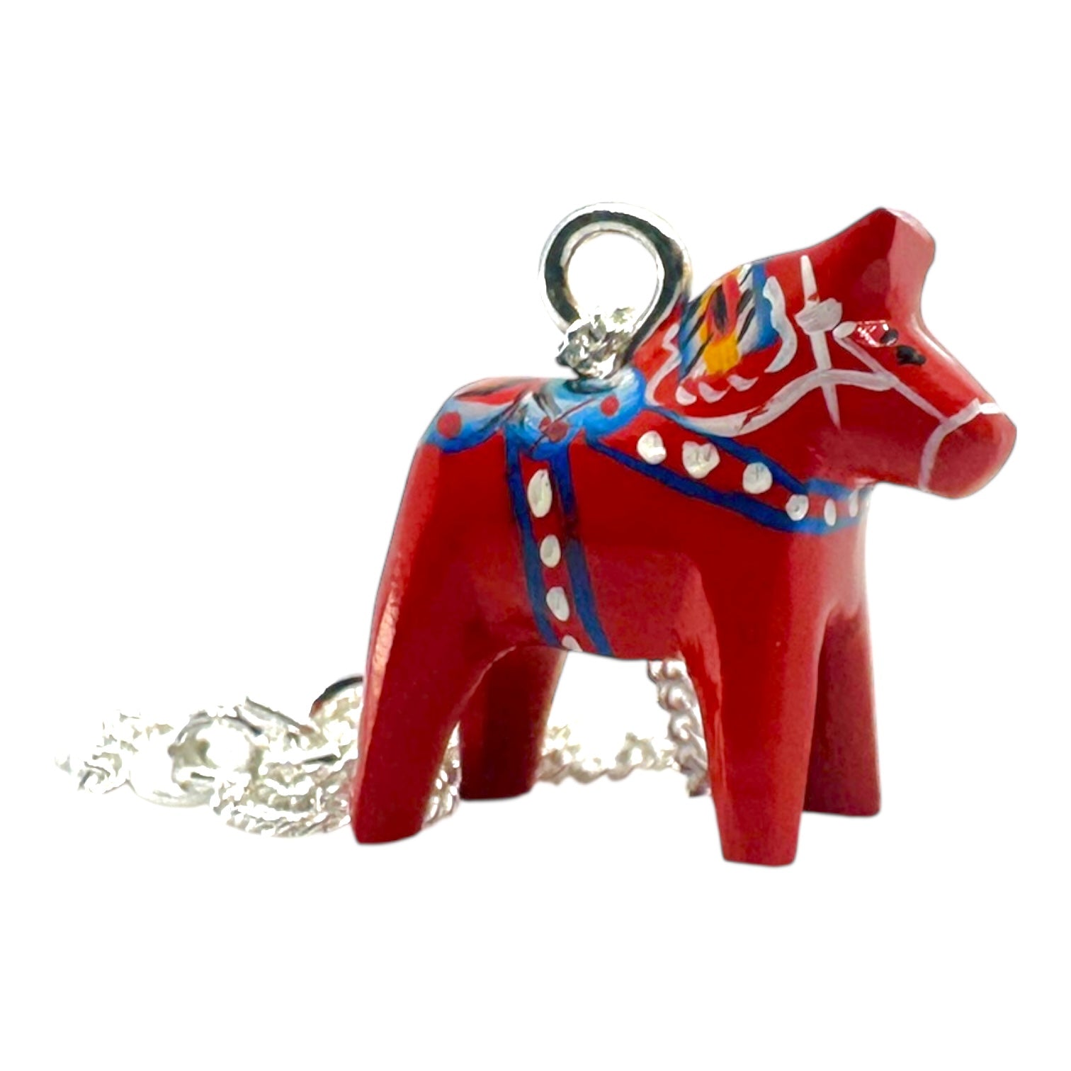 The Red Dala Horse Necklace features a 2cm handcrafted pendant inspired by Swedish Folk Art, painted in blue, yellow, and white, on a 19 sterling silver chain.
