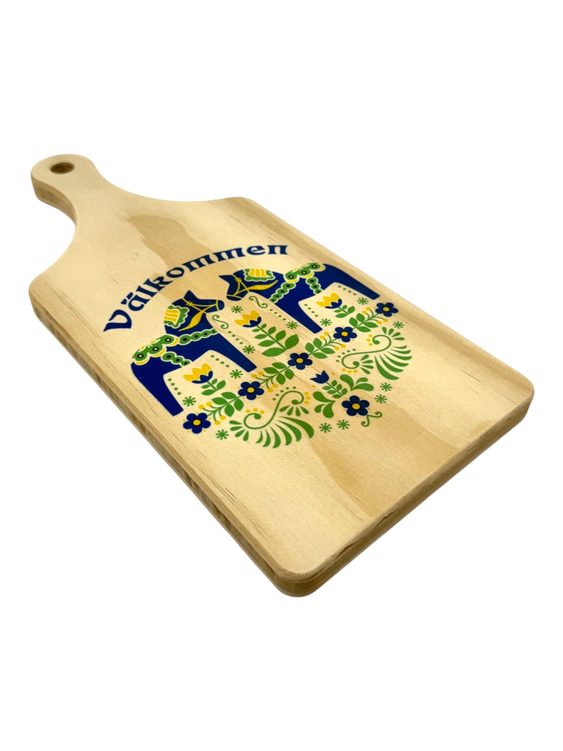 A bamboo cutting board with a handle features a blue Dala horse folk art design inspired by Scandinavian style and has “Välkommen” printed at the top.