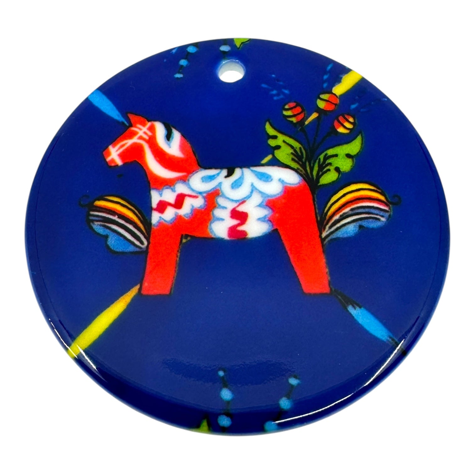 The Ornament: Dala Horse Ceramic 3 is a round blue ceramic piece with a red Dala horse and floral motifs, capturing Scandinavian charm. It features a small hole at the top for easy hanging.