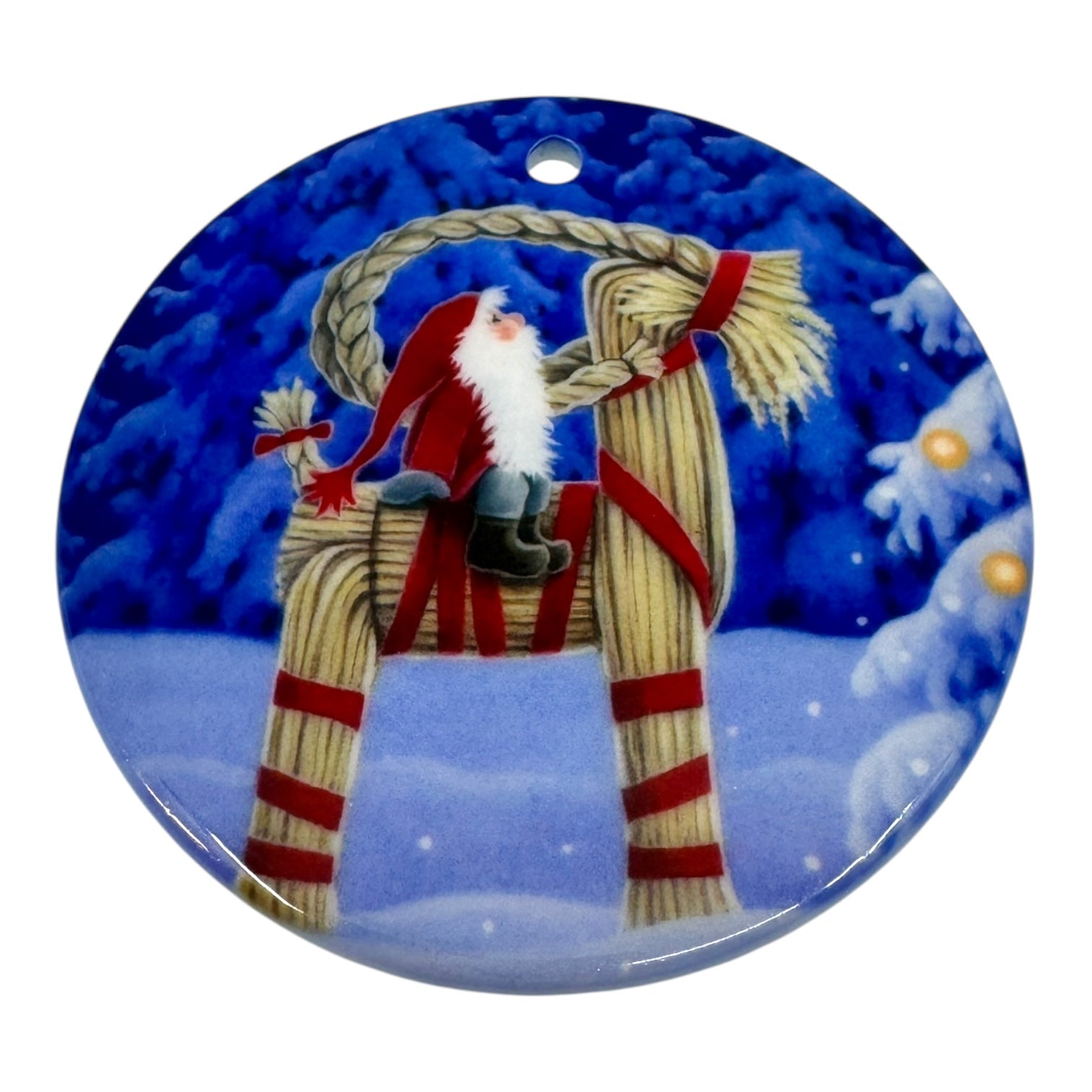 Celebrate the season with the 3" round Ornament: Tomte on Straw Goat by Eva Melhuish, showcasing a Scandinavian Santa (Tomte) riding a straw Julbock against a wintry forest backdrop.