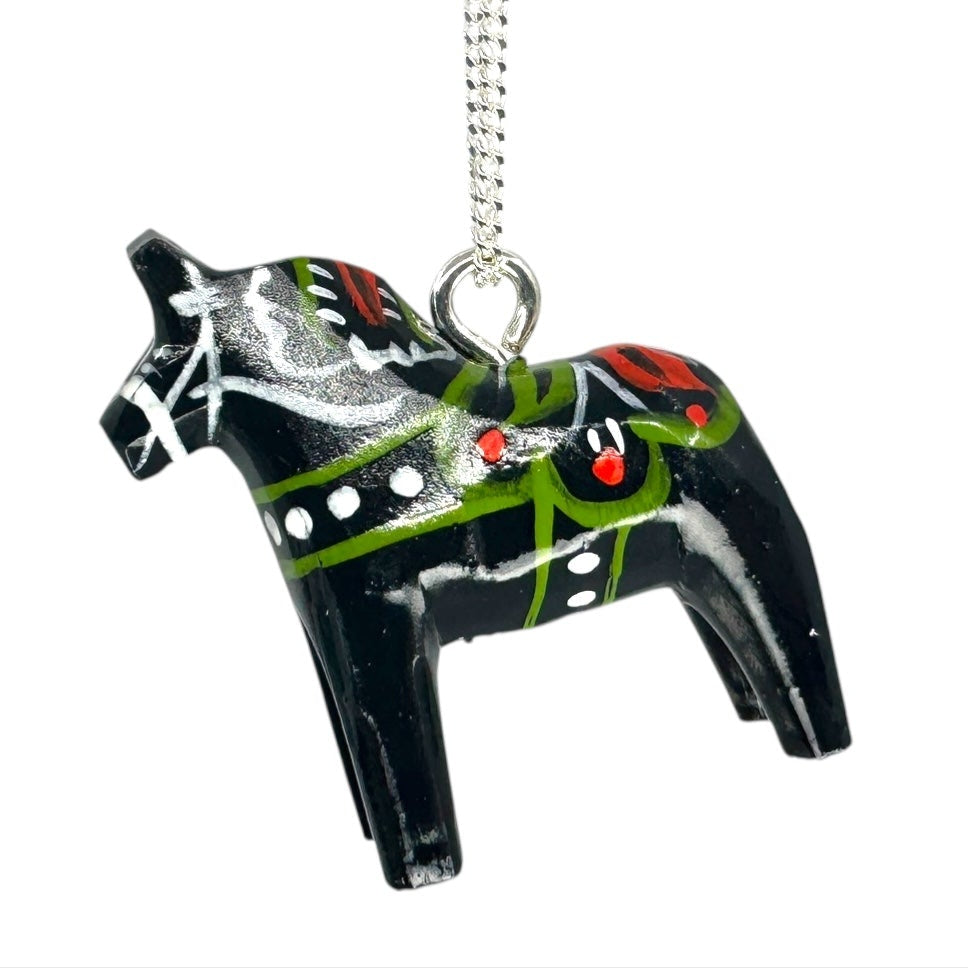 The Necklace: Black Dala Horse Necklace – Handcrafted Pendant highlights Swedish artistry with red, green, and white floral patterns on a black horse pendant, suspended from a silver chain.