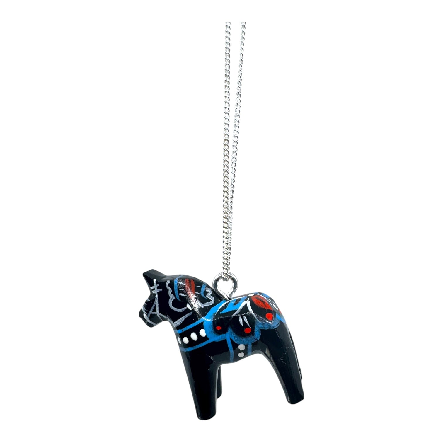 The Black Dala Horse Necklace features a handcrafted silver chain and a black pendant inspired by Scandinavian folk art, adorned with blue, red, and white painted decorative patterns.