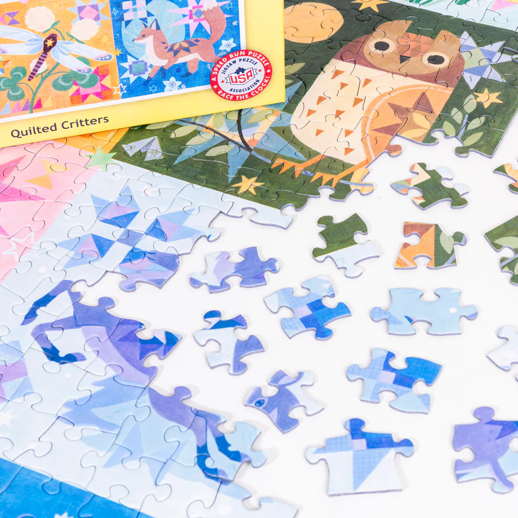 Partially completed PuzzleTwist: Quilted Critters 500-piece puzzle by Mirka Hokkanen, featuring an owl, with unassembled blue and white pieces scattered nearby.