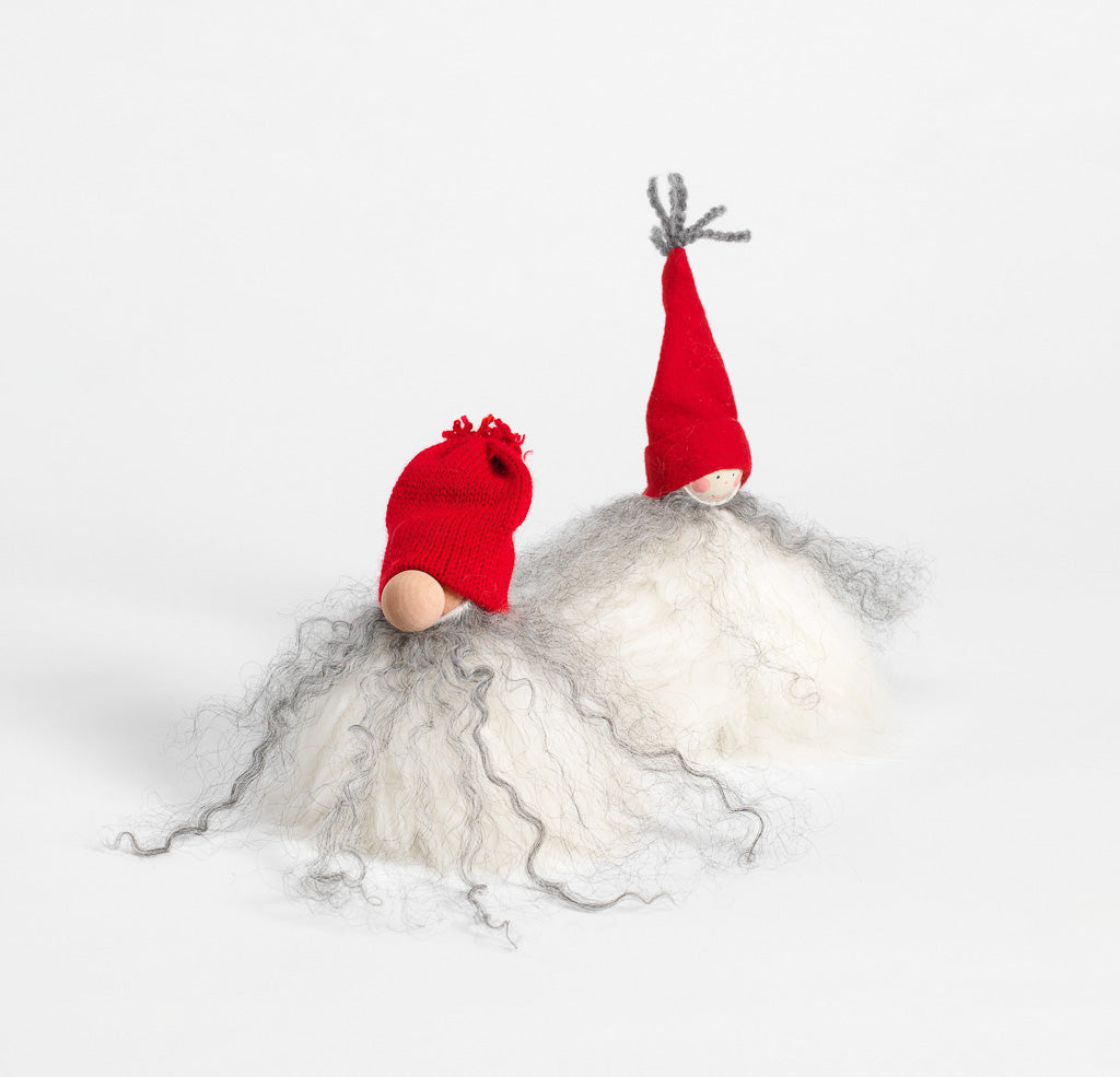 A pair of Swedish Gnome "Santa" figurines with wood and wool bodies, red caps, and long white and gray beards are handcrafted in Sweden and set against a plain white background.