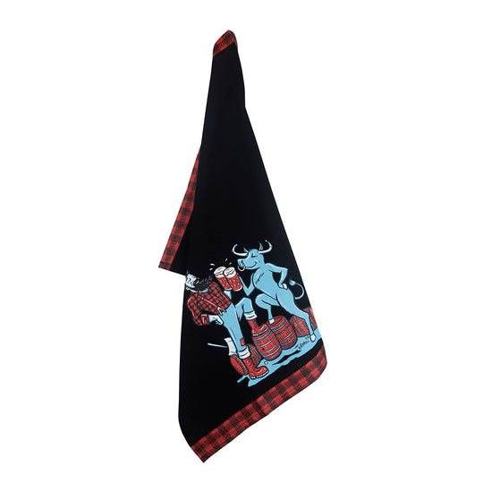 The Tea Towel: Paul & Babe Cheers! Tea Towel by Adam Turman features a black design with a red plaid border, showcasing an illustration of Paul Bunyan, Babe the Blue Ox, and two people standing on barrels.