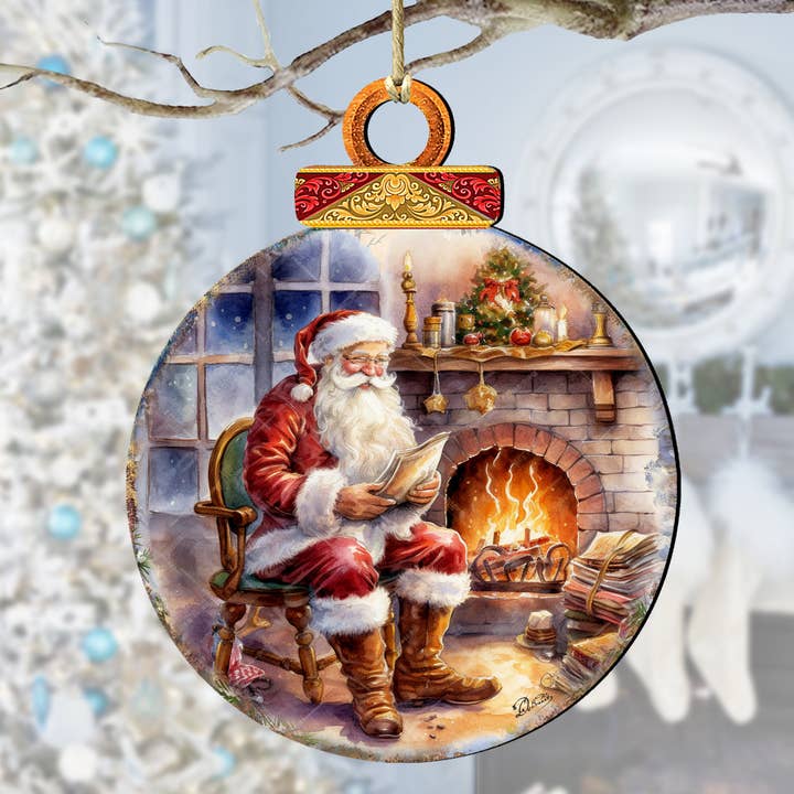 The Ornament: Santa by the Fireplace Wood Ornament (4.5" x 4" approx) features a handcrafted scene of Santa reading by a festive mantel and glowing fire, making it a cozy and charming keepsake for your Christmas tree.