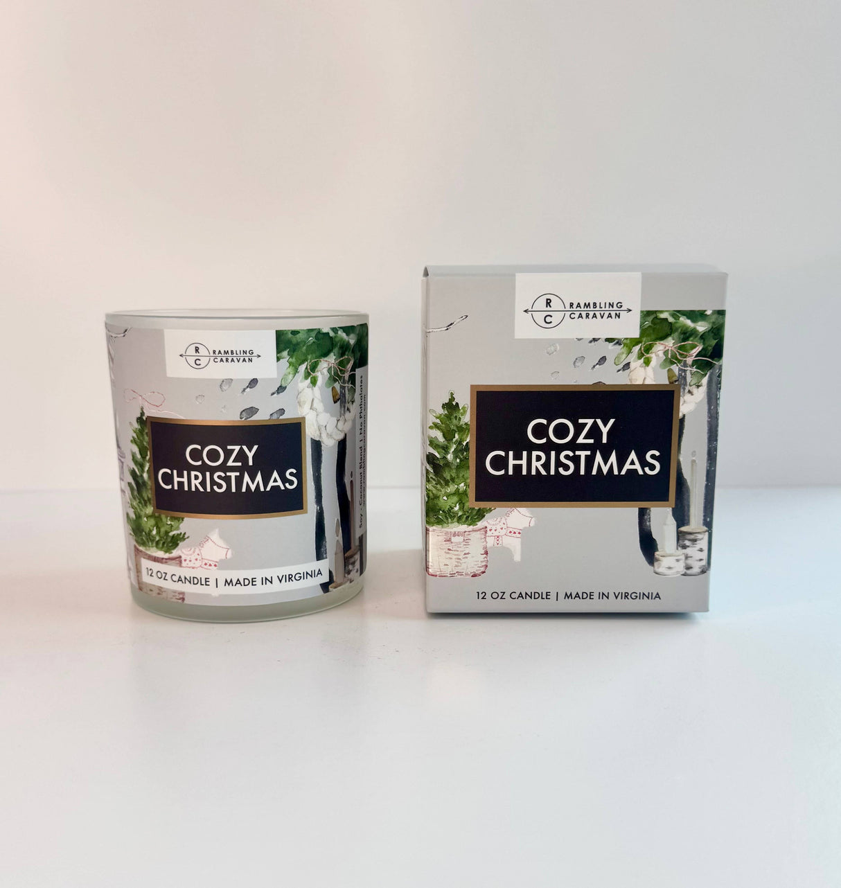 The Cozy Christmas Candle 12 oz from Rambling Caravan is made in Virginia and comes boxed with green foliage packaging—a simple, festive design perfect for enjoying a warm holiday fragrance at home.