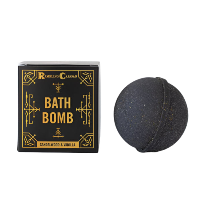 A black Bath Bomb: Sandalwood & Vanilla is displayed beside its box, which features gold text and decorative accents on a black background, emphasizing its nourishing ingredients.