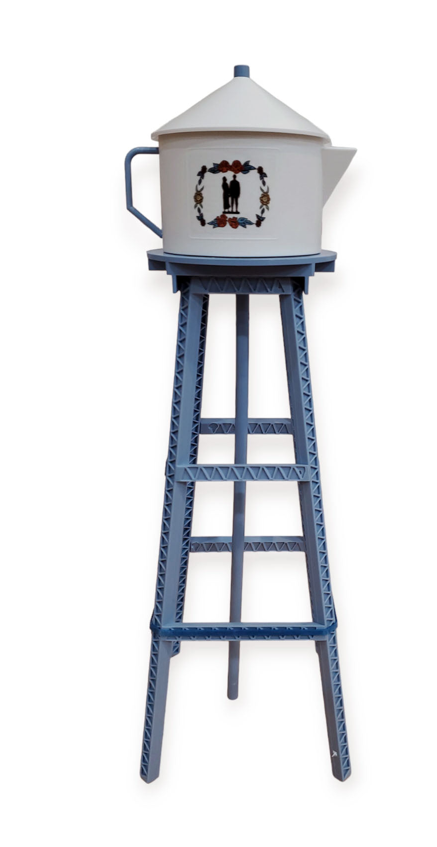 The Model Kit: Miniature Replica of the Lindström Coffee Pot Water Tower features a white metal coffee pot with spout and lid displayed on a tall blue decorative four-legged metal stand.