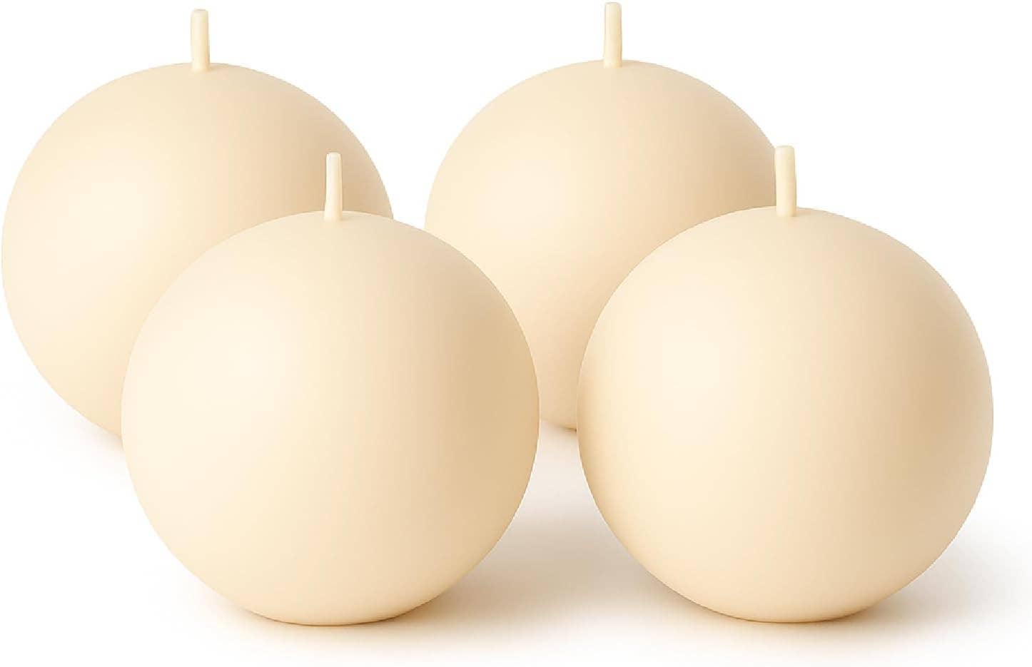 Four round, cream-colored Champagne Ball Candles (2.5" diameter) with short wicks are arranged together against a white background, adding an elegant and unscented decorative touch to any setting.