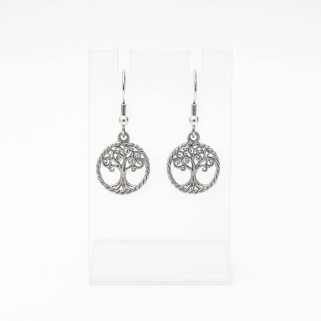 The Tree of Life Round Drop Silver Earrings feature handcrafted round silver dangle designs, shown on a clear stand with a white background.