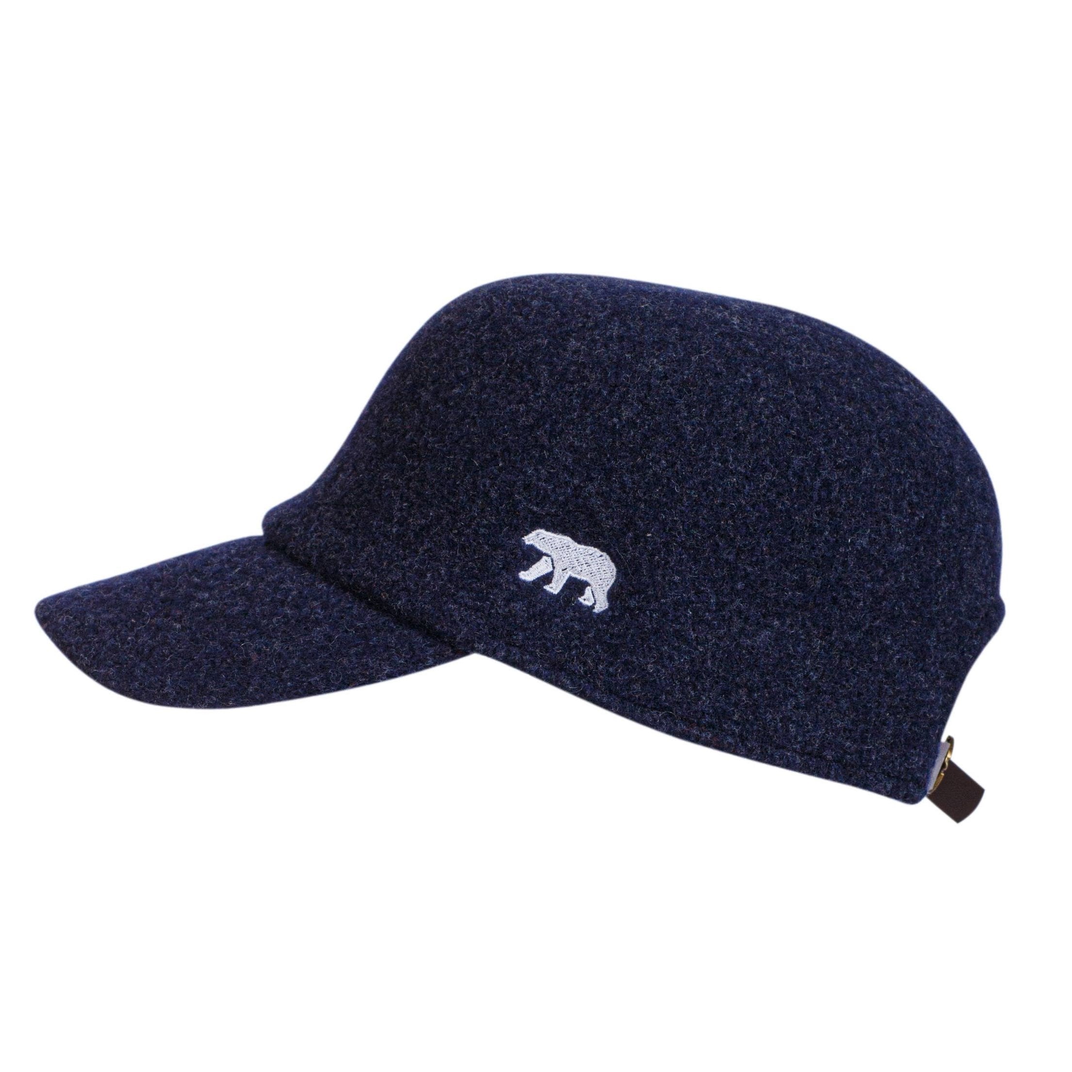 The Hat: Woolen Baseball Cap Navy by Norlender in Norway is a navy wool cap with an adjustable strap and a small white bear emblem, inspired by classic Norwegian knitwear.