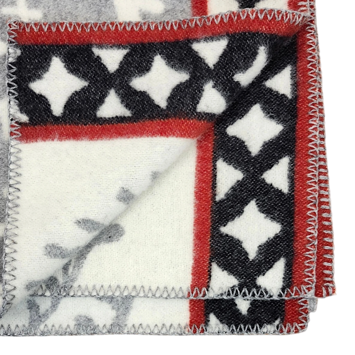 Close-up of a Swedish wool blanket featuring black, white, and red geometric patterns with zigzag stitching along the edges.