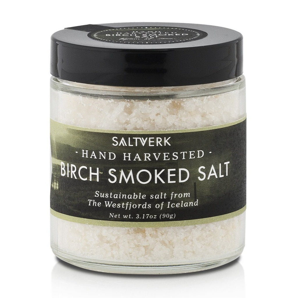 A clear jar labeled Saltverk - Birch Smoked Salt (90g, 3.17oz), containing coarse hand-harvested sustainable salt from the Westfjords of Iceland, highlighting its Icelandic tradition.