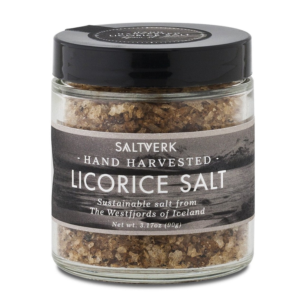 A 90g glass jar of Saltverk Hand Harvested Licorice Salt from the Westfjords of Iceland, featuring flaky sustainable sea salt crystals and a black screw-on lid.