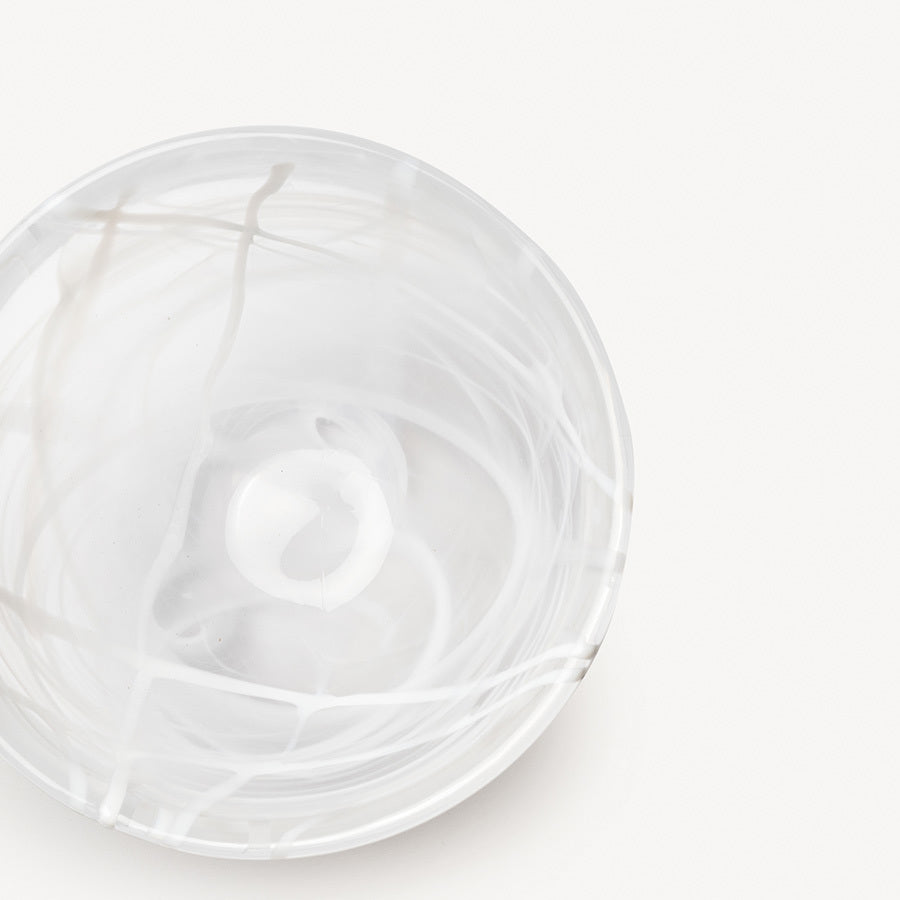 A round, clear KostaBoda Contrast Bowl by Anna Ehrner, featuring elegant white with blue and black veining, displayed on a plain white background.