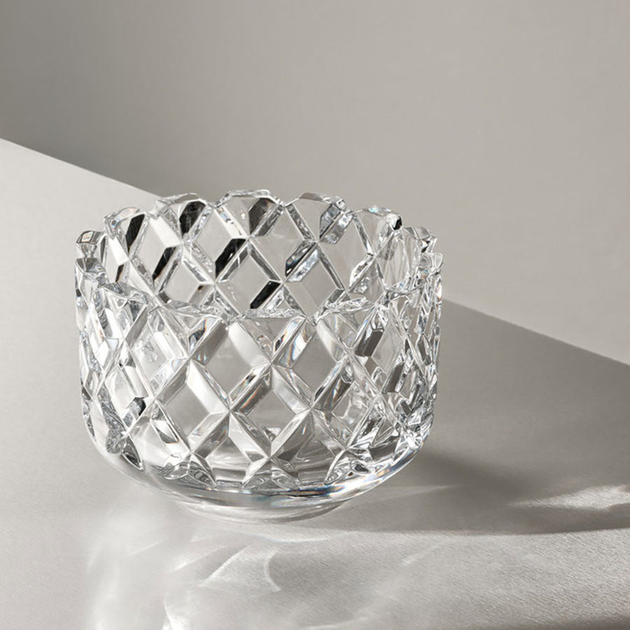 The Orrefors: Sofiero Bowl Medium, designed by Gunnar Cyren, features a clear crystal with a diamond-cut pattern and sits on a white surface, casting geometric shadows.
