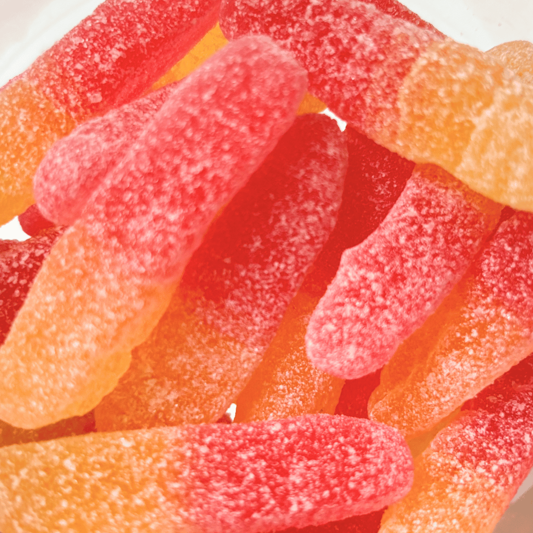 A close-up of red and orange sour gummy worms from the Swedish Candy Bag, coated in sugar.