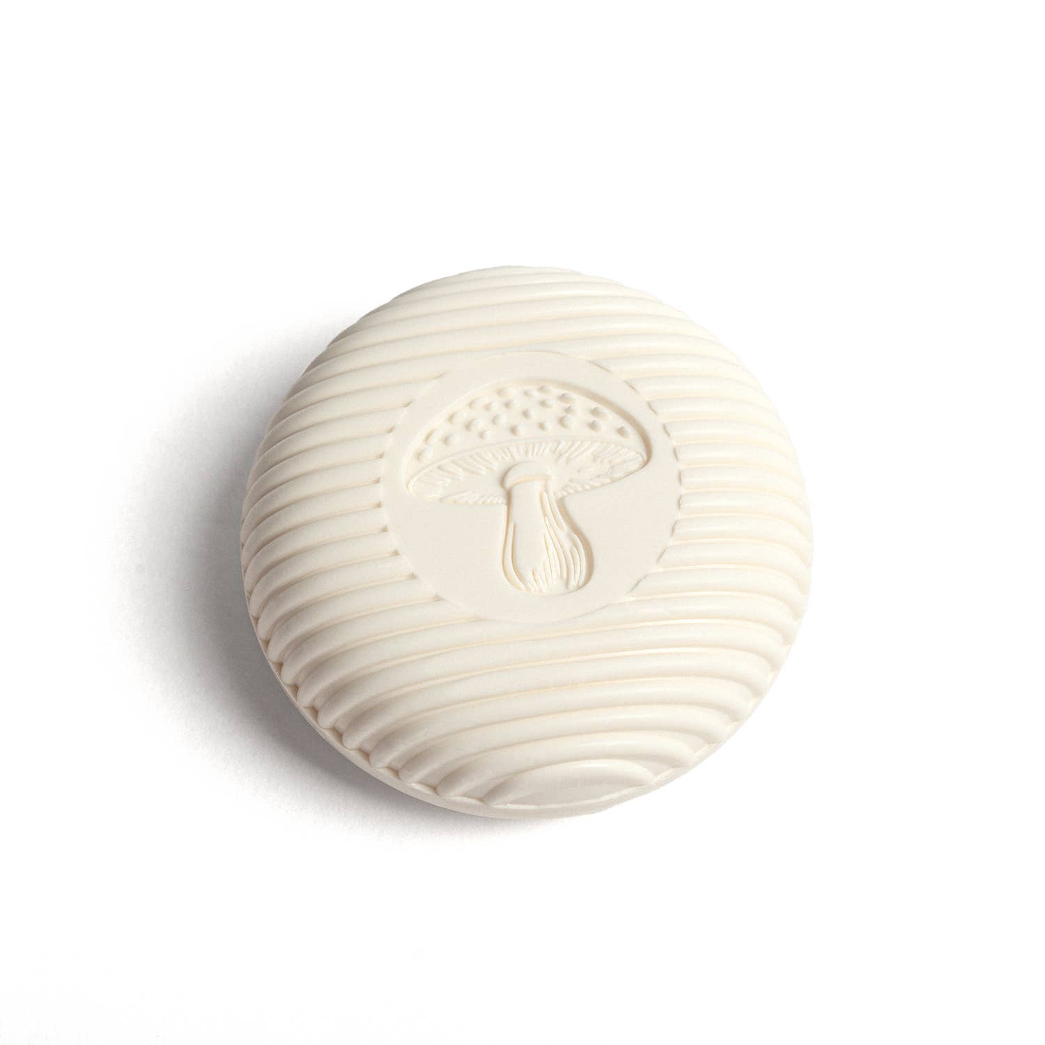 An off-white, round bar of Swedish Dream Gnome Soap features a textured surface and a raised mushroom design in the center, evoking a whimsical, natural-world charm.