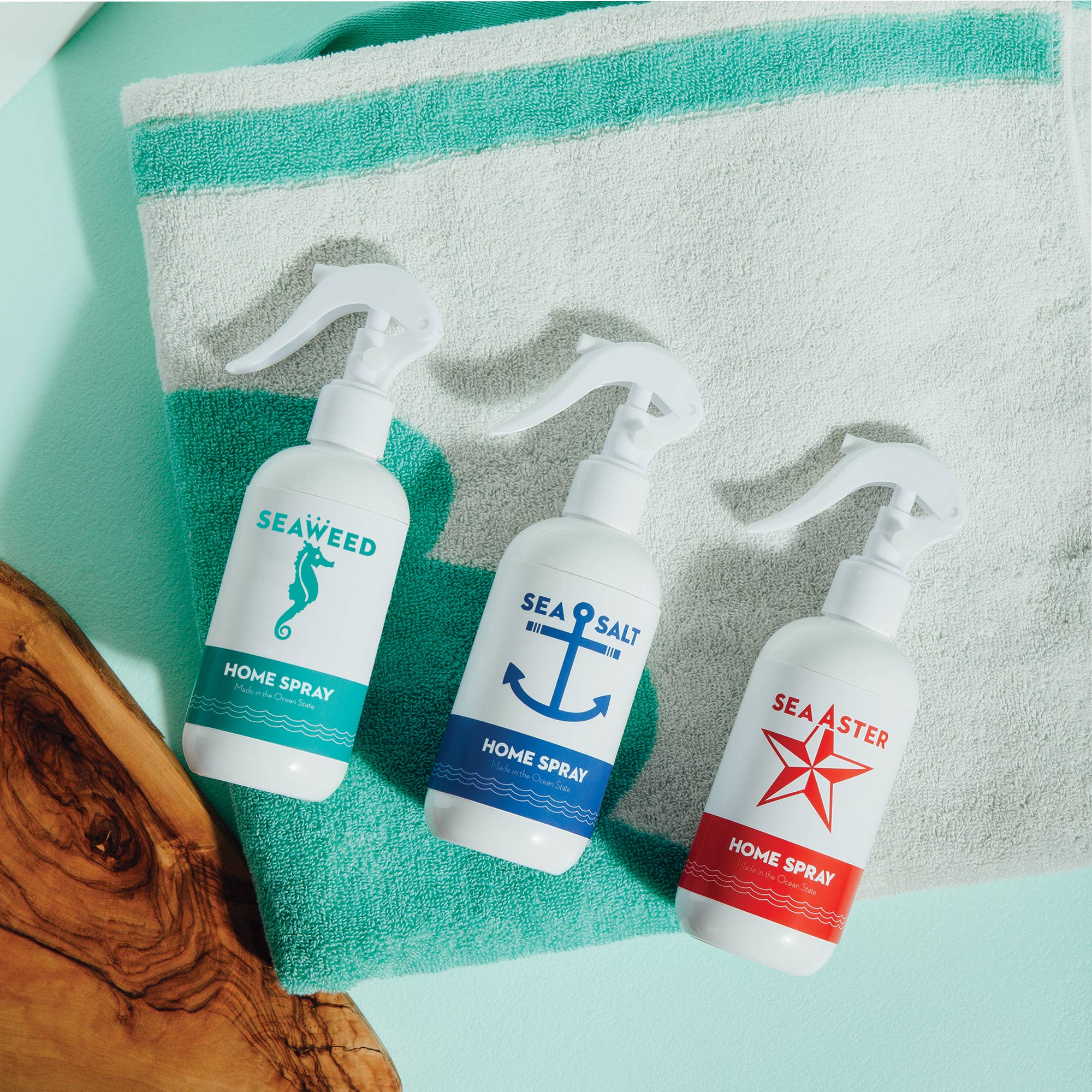 A white bottle of Swedish Dream® Sea Salt Home Spray 8 fl oz sits on a folded white towel with green stripes atop a light blue surface, evoking ocean air in a cruelty-free formula.