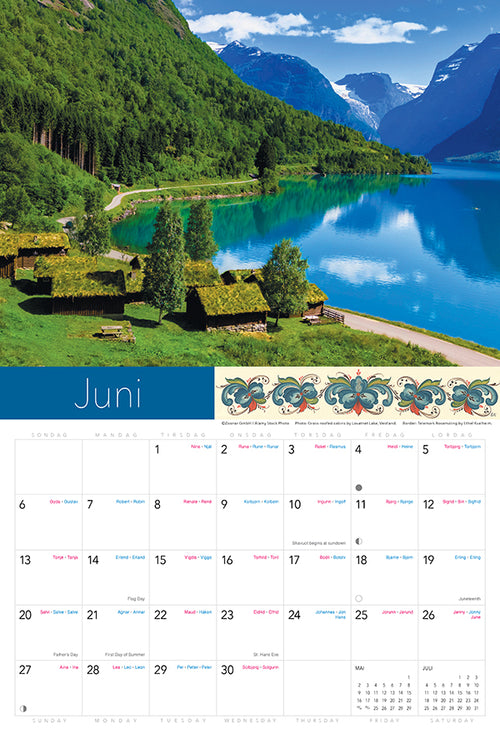 2027 wall calendar page for June featuring a lake, green mountains, and grass-roofed houses beneath a blue sky; month dates shown below the landscape image.