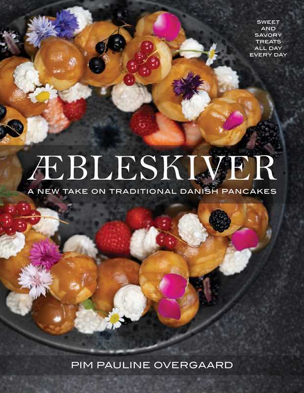 A wreath of Danish pancakes (Aebleskiver) with cream, berries, and flowers decorates the cover of Book: Aebleskiver by Pim Pauline Overgaard A New Take on Traditional Danish Pancakes.