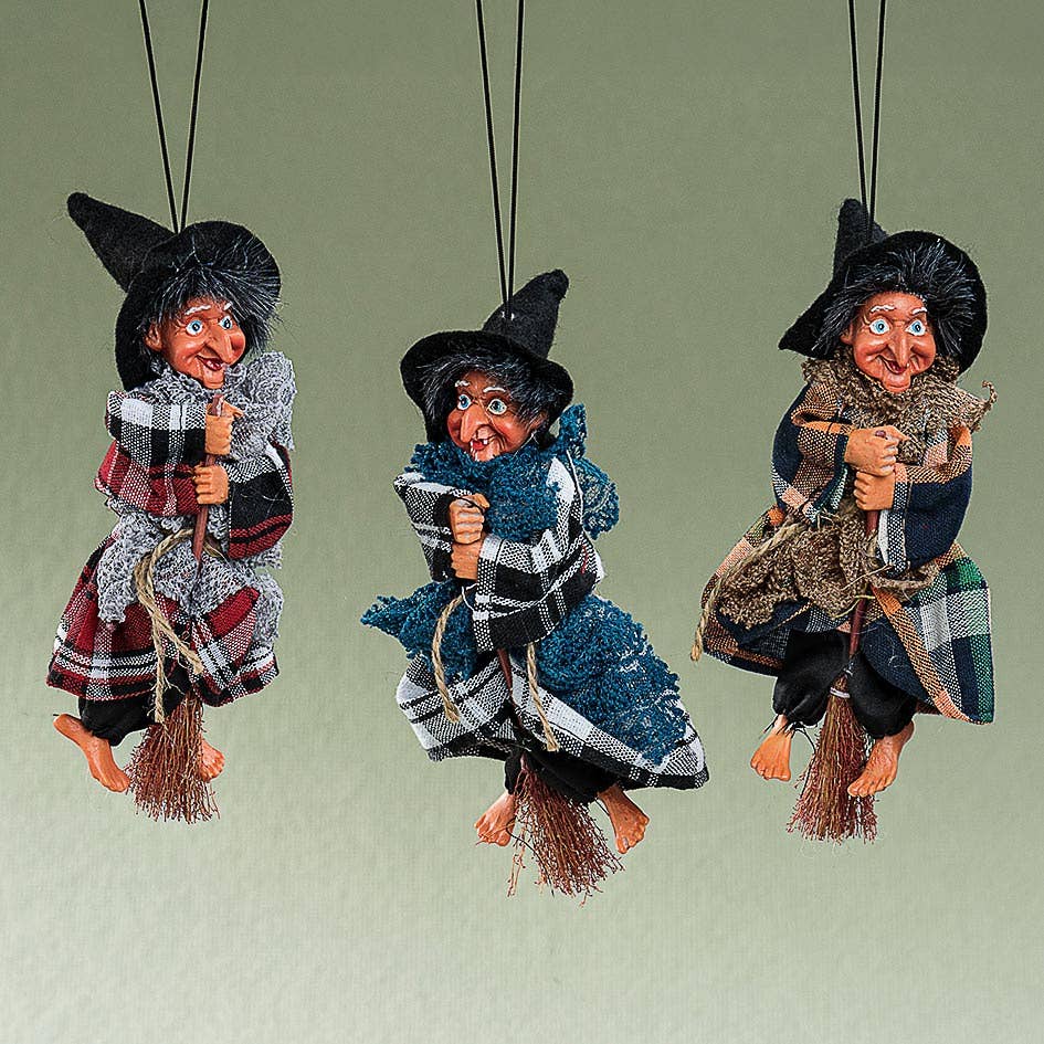The Kitchen Witch: Minna Red Doll, in a plaid robe and black hat, sits on a broom suspended by string—perfect as a folklore-inspired kitchen decor piece and charming good luck doll for your home.
