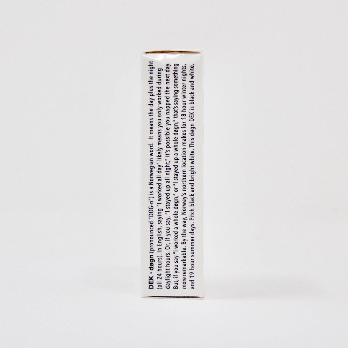 The side view of the DEK Døgn (Norway) playing card box displays text in blue. The predominantly white, rectangular box captures a distinctive aesthetic influenced by Norwegian design.