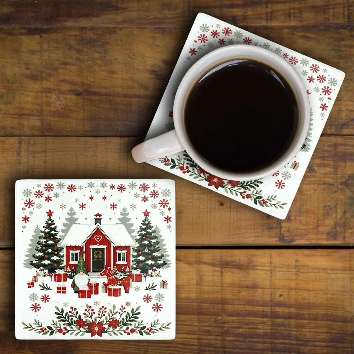 Square Nordic ceramic coaster featuring a red house, a tomte, and Christmas trees, with a coffee mug on a matching Swedish folk art coaster atop a wooden surface.