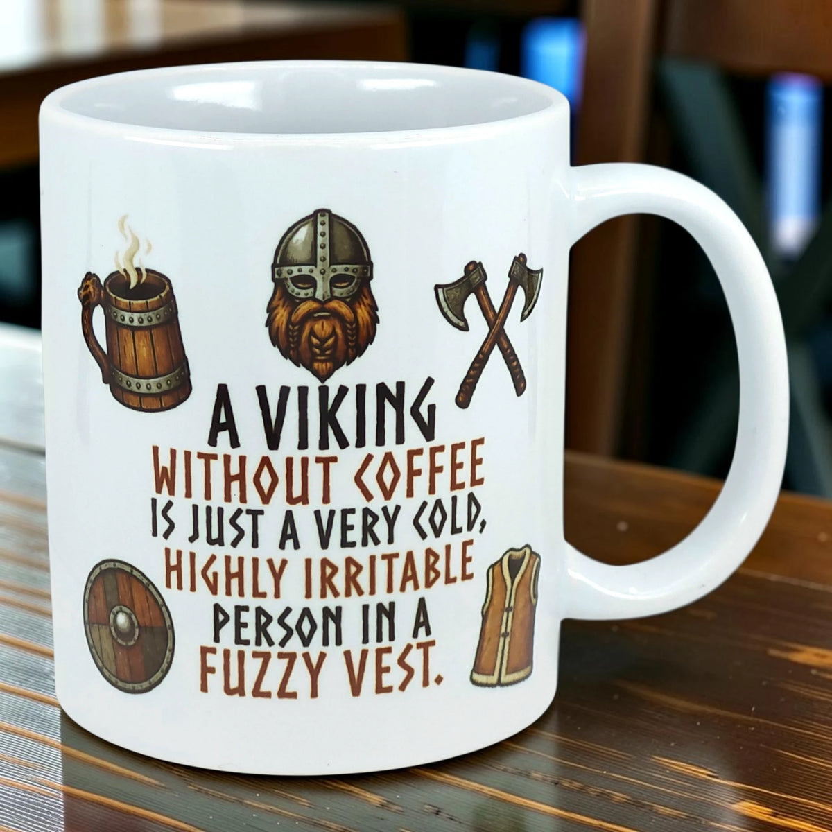 White ceramic mug with Nordic-themed cartoon Viking and printed text: “A Viking without coffee is just a very cold, highly irritable person in a fuzzy vest.”.