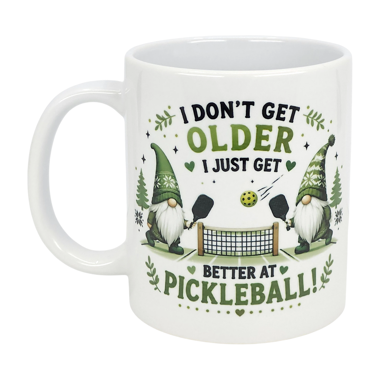 The Nordic Wholesale "Better at Pickleball" ceramic gnome mug (11 oz) features two Nordic gnomes playing pickleball, surrounded by leaves and hearts, with the message: I don't get older, I just get better at pickleball!.