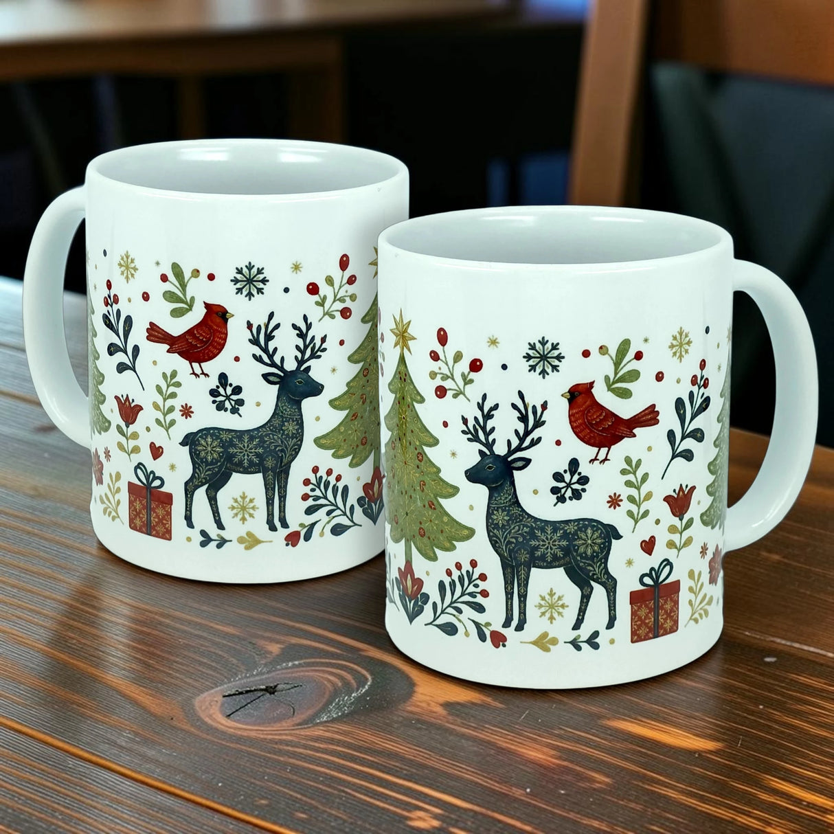 Two Nordic Wholesale "Nordic Forest Reindeer & Christmas Tree" ceramic mugs (11 oz), featuring festive designs with reindeer, red birds, Christmas trees, holly, and gift boxes, sit on a wooden table.
