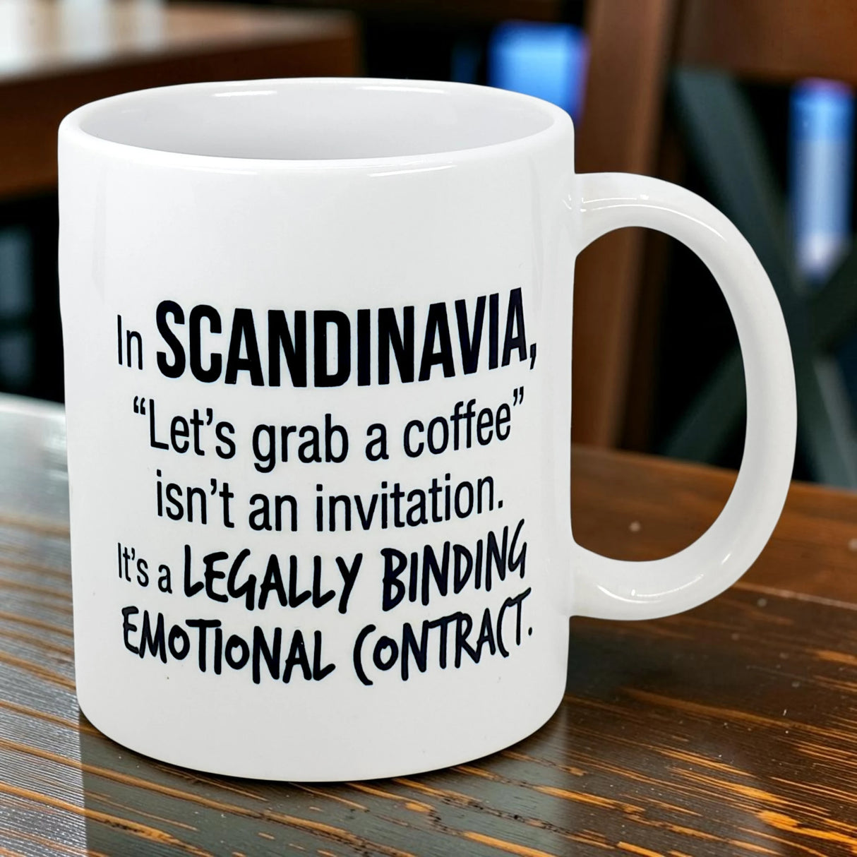 The Swedish Gift Store’s 11 oz Mug: Scandinavia Coffee Legally Binding Emotional Contract features black text on white ceramic: “In SCANDINAVIA, ‘Let’s grab a coffee’ isn’t an invitation. It’s a LEGALLY BINDING EMOTIONAL CONTRACT.”.