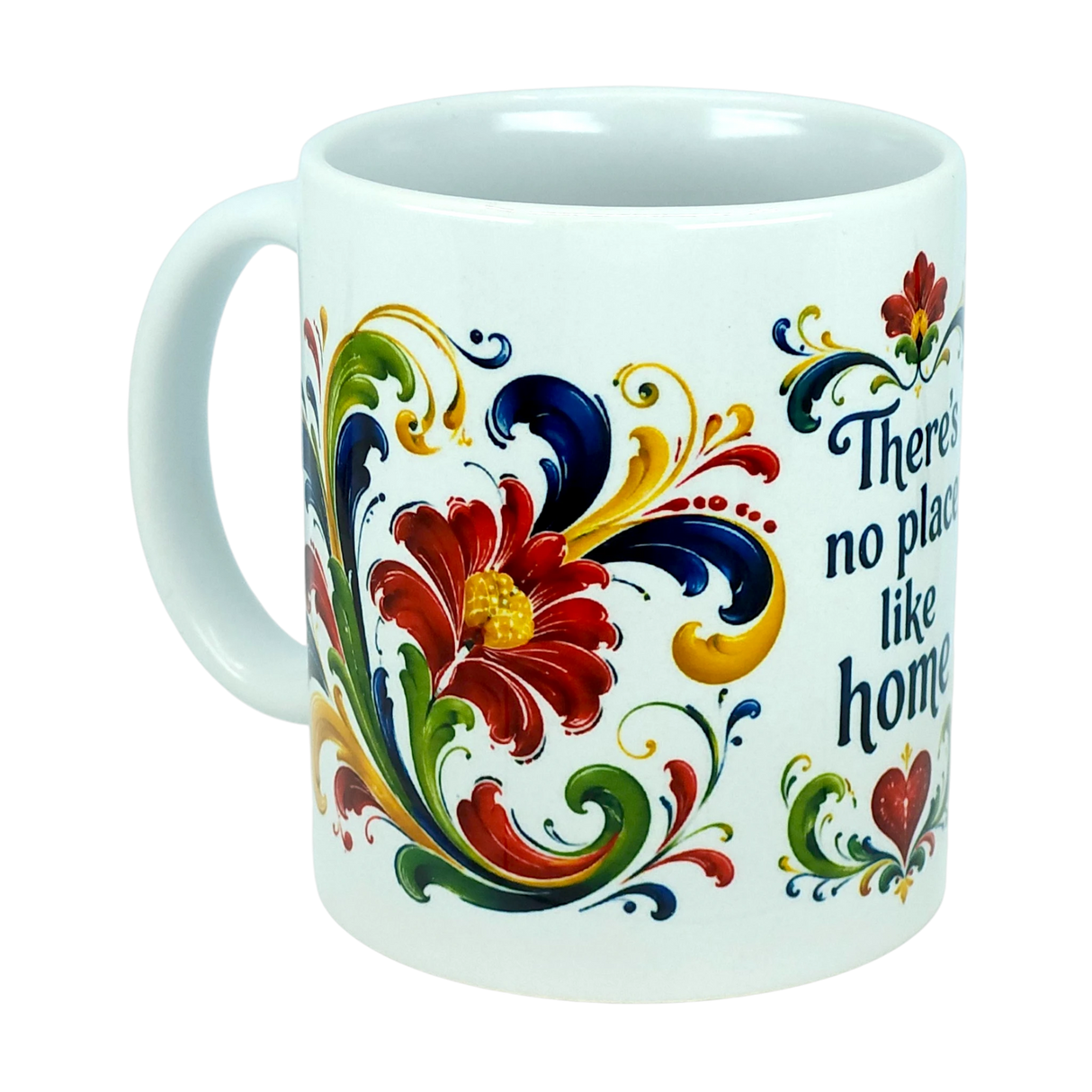 The Mug: There's No Place Like Home Rosemaling Ceramic Mug (11 oz) by Nordic Wholesale is a white ceramic coffee mug featuring red, yellow, blue, and green floral designs inspired by Scandinavian folk art. Ornate swirls reminiscent of traditional Norwegian Rosemaling surround the flowers, and the partial phrase "There's no place like home" appears in blue text on the mug.