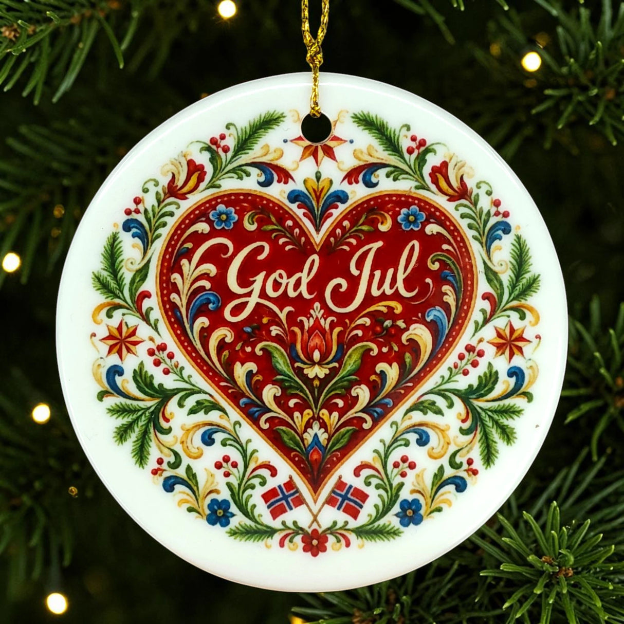 Nordic Christmas ornament featuring a red heart, floral patterns, and “God Jul” text. Two small Norwegian flags are positioned at the bottom. Ornament hangs on a tree.