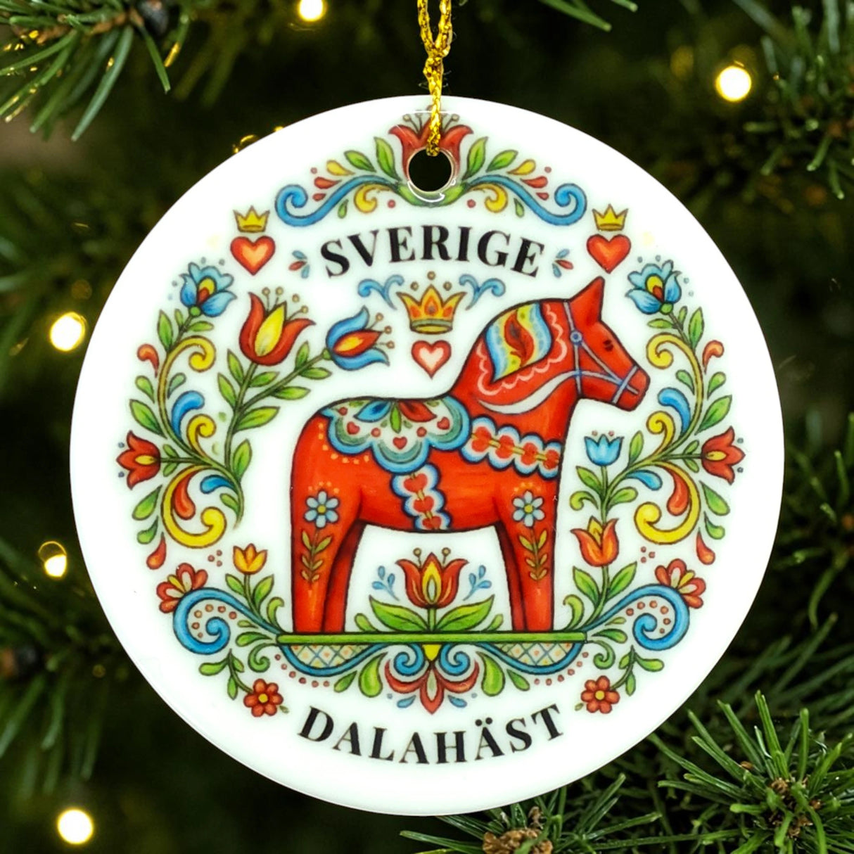 Round ornament with a red Dala horse decorated in colorful floral patterns and the words SVERIGE DALAHÄST, shown hanging on a Christmas tree branch.