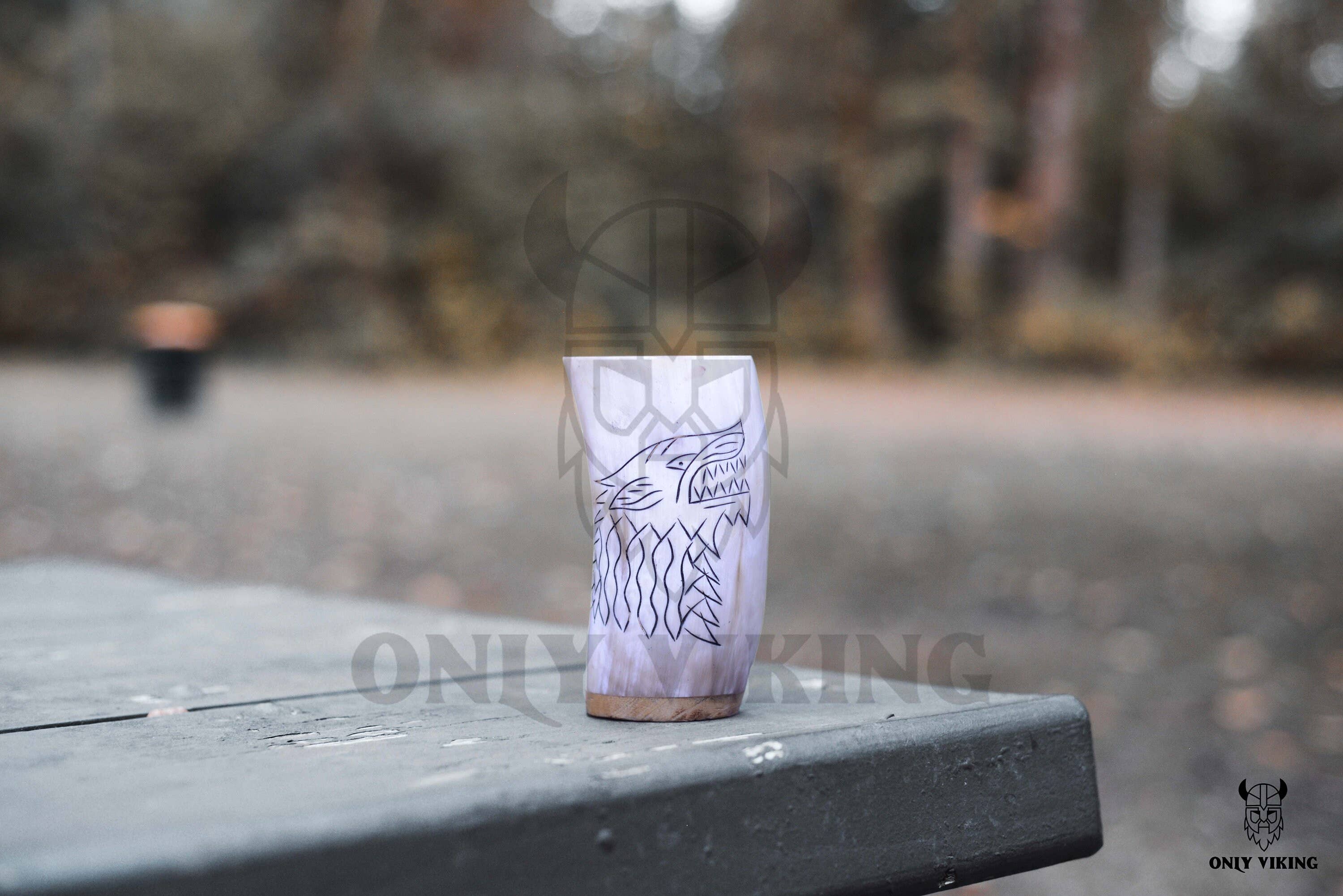 The Horn Mug: Beer Stein Drinking Horn Mug Tree of Life 6-9 oz, featuring a classic design, sits on a rustic outdoor table with trees blurred in the background.