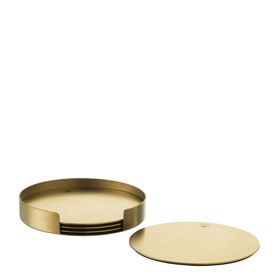 The Orrefors Peak Non-Slip Coasters, designed by Martti Rytkönen, come in a set of four gold-colored round coasters with one displayed flat and others stacked in a holder.