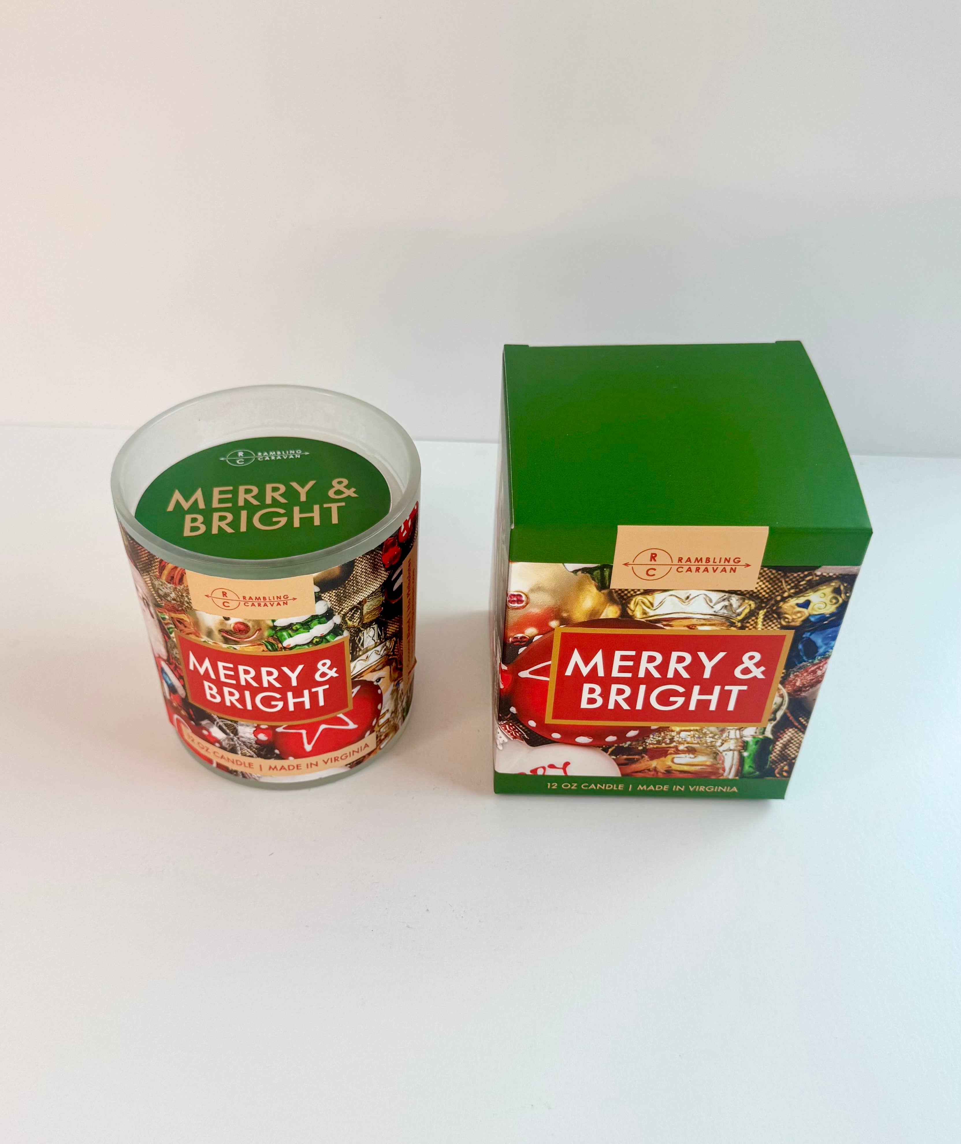 The Merry & Bright Candle 12oz and its festive box are displayed on a white surface. This premium candle is perfect for adding a cozy, cheerful holiday touch to your space.