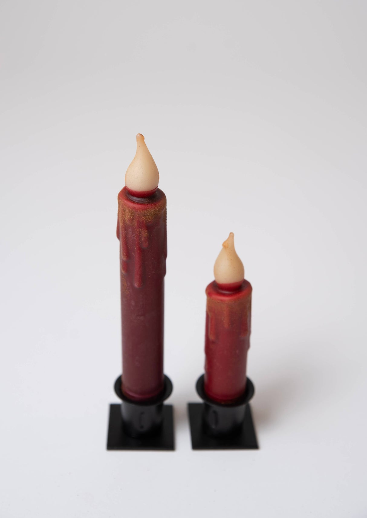 The 7" Burgundy Cinnamon Dusted LED Timer Taper Candle stands upright in a black holder, featuring a realistic flame effect—perfect for adding cozy charm to your farmhouse home décor.